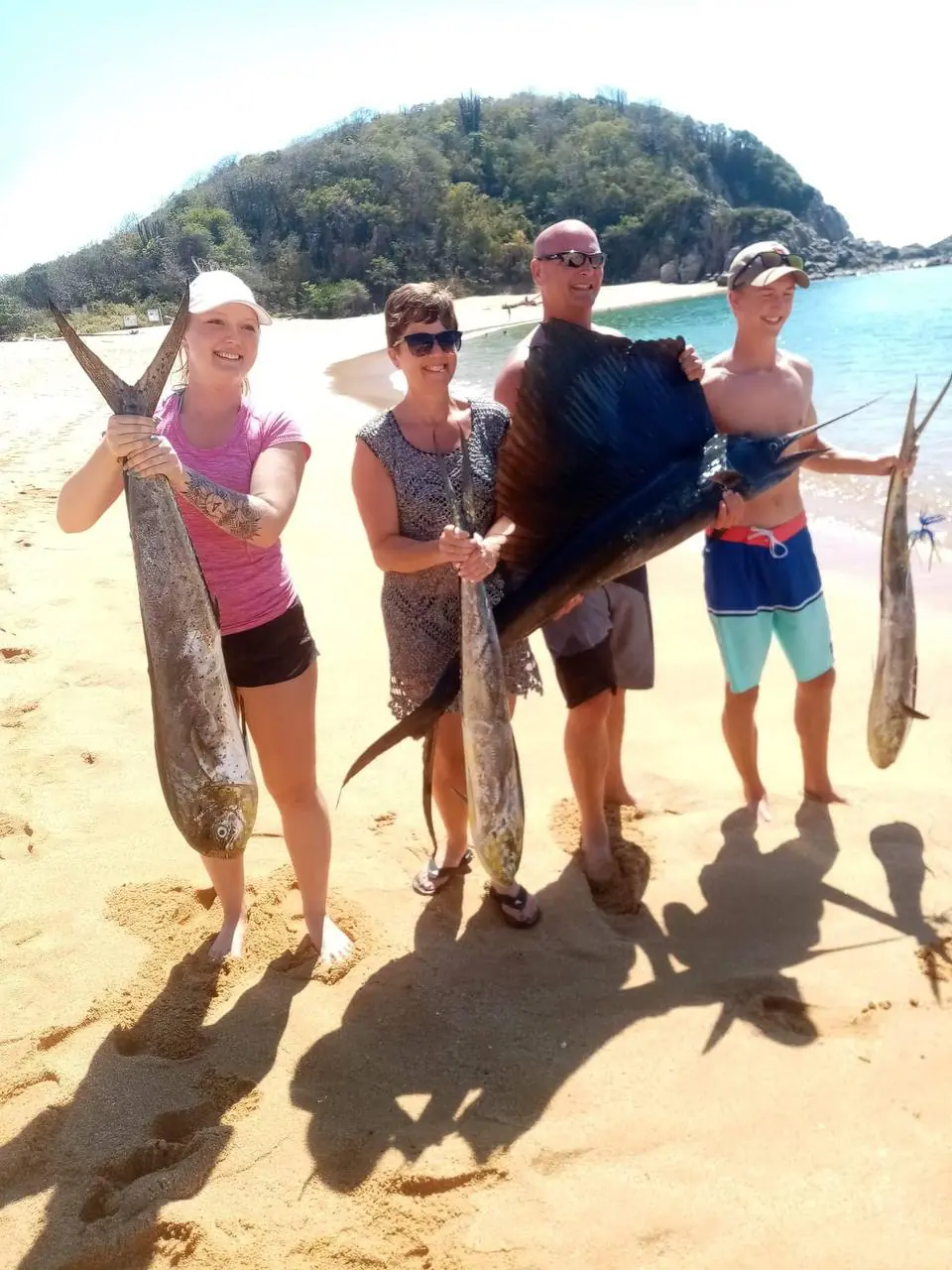 Grupo en la playa con un marlín y dorados